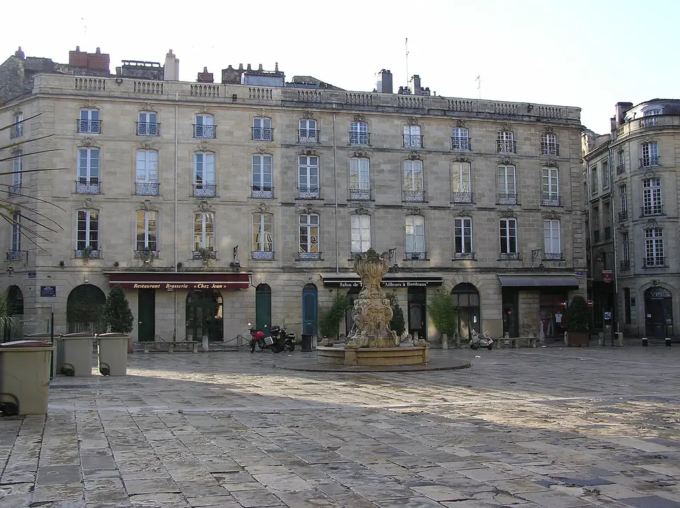 Place du Parlement à Bordeaux, immeubles classiques en pierre blonde aux hautes fenêtres à balcons en fer forgé, autour d'une fontaine sculptée.
